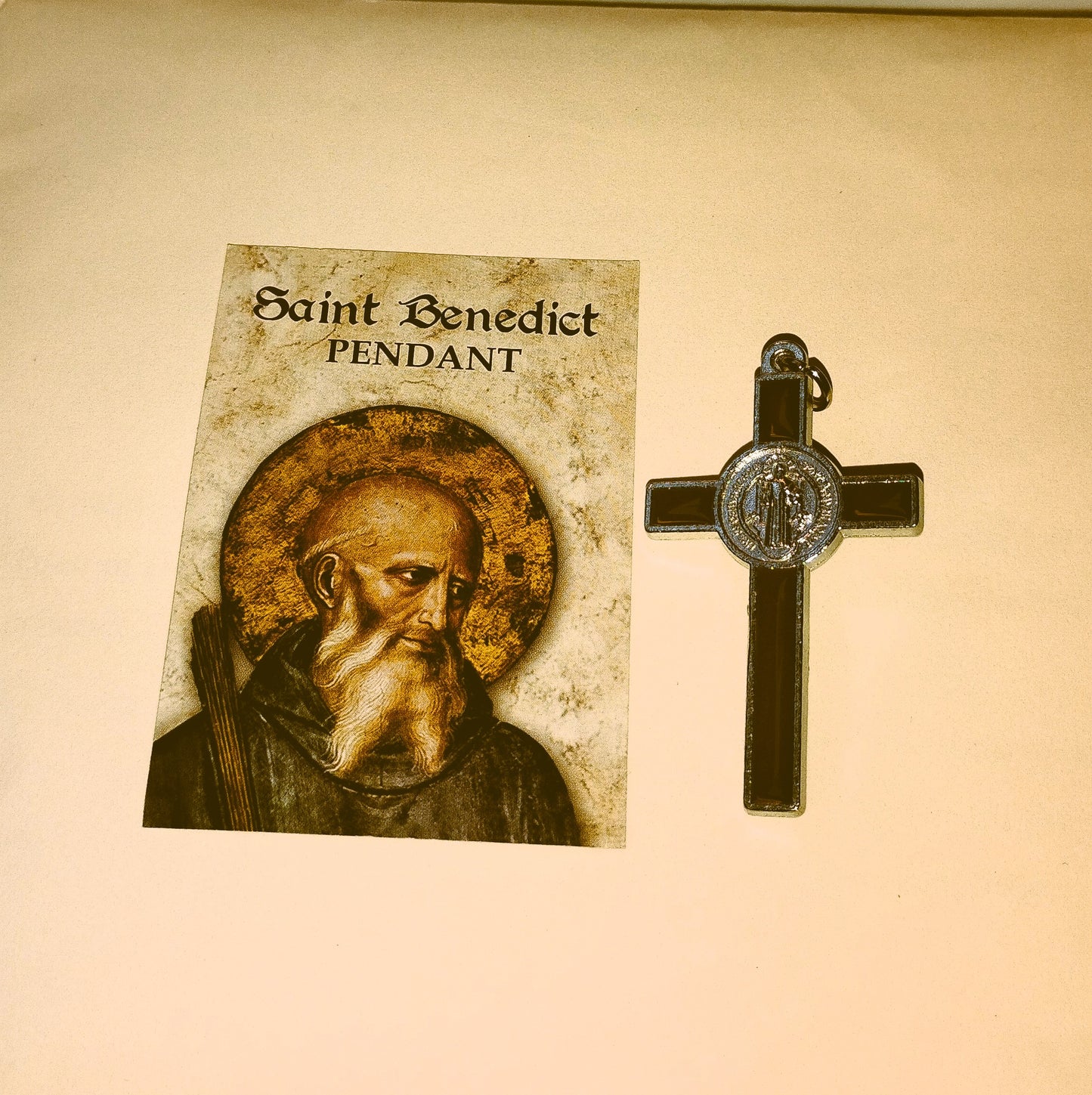 Saint Benedict crucifix with an illustration of the saint on a beige background