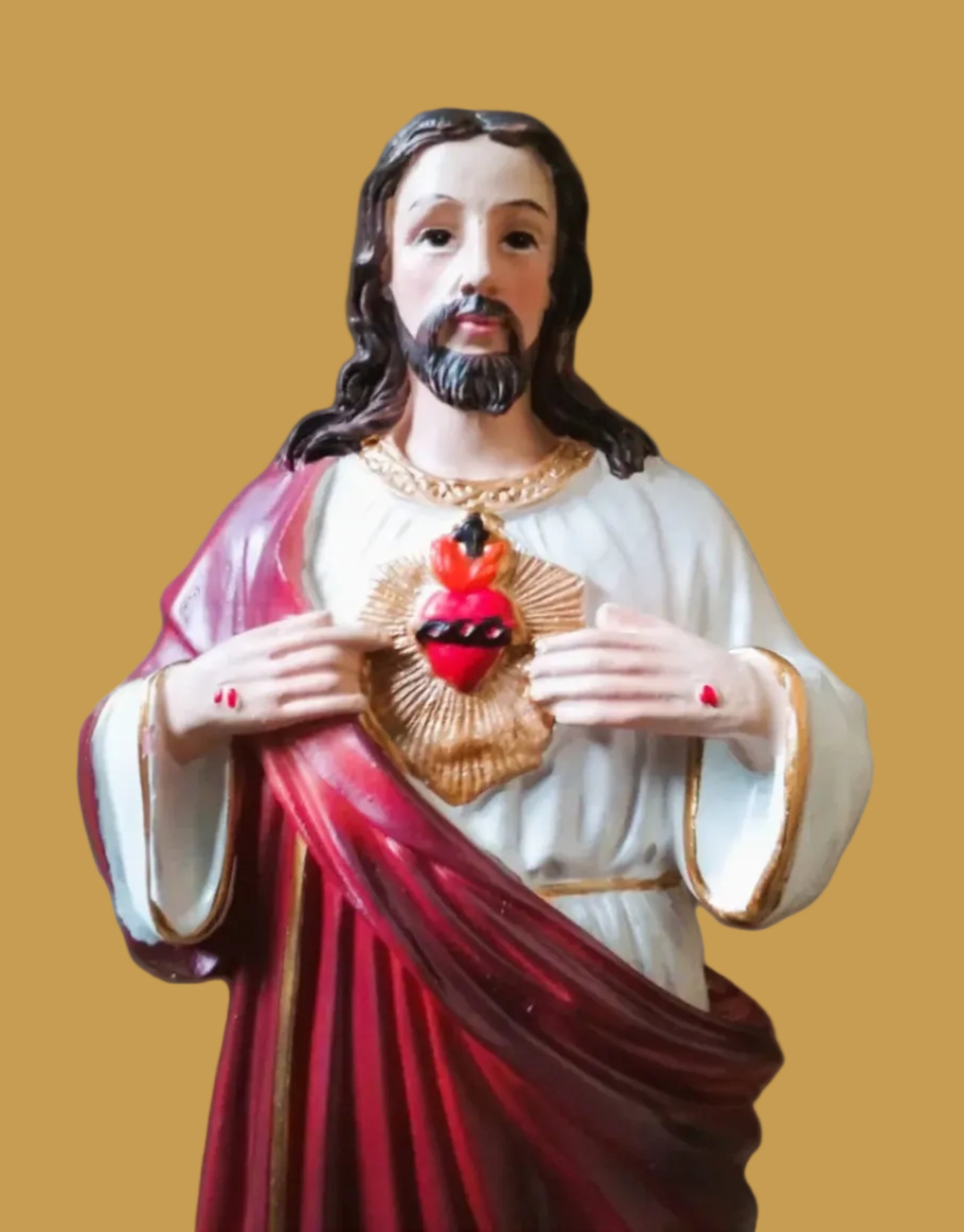 Statue of a religious figure holding a Sacred Heart emblem against a red background